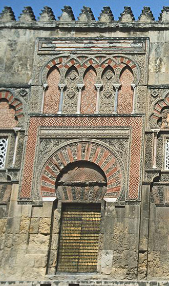 Detail of one of the entrances of the Great Mosque of Cordoba, (10th century) showing a panel of intersecting arches above the door. Note the colour combination as well.
